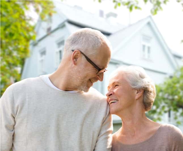 elderly couple standing outside of home