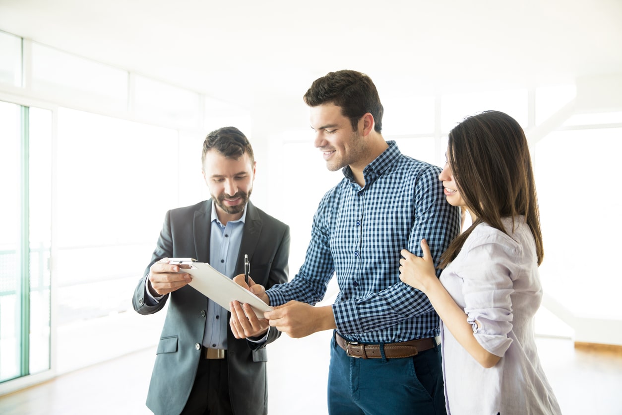 Couple Signing Agreement By Real Estate Agent In New Apartment