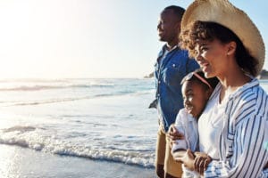 a family standing on the beach looking at the ocean