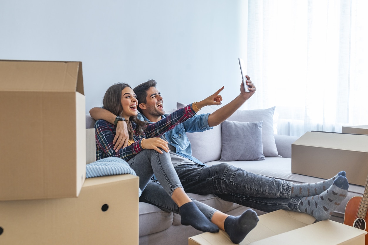 Young couple taking selfies with her tablet in their new home