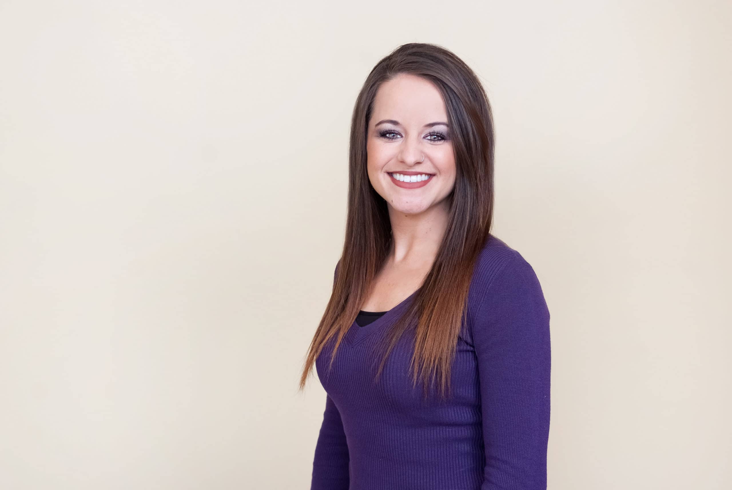 a woman in a purple sweater smiles for the camera