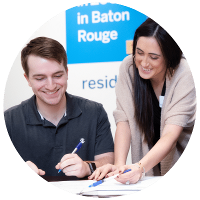 a man and a woman sit at a table in front of a sign that says in baton rouge