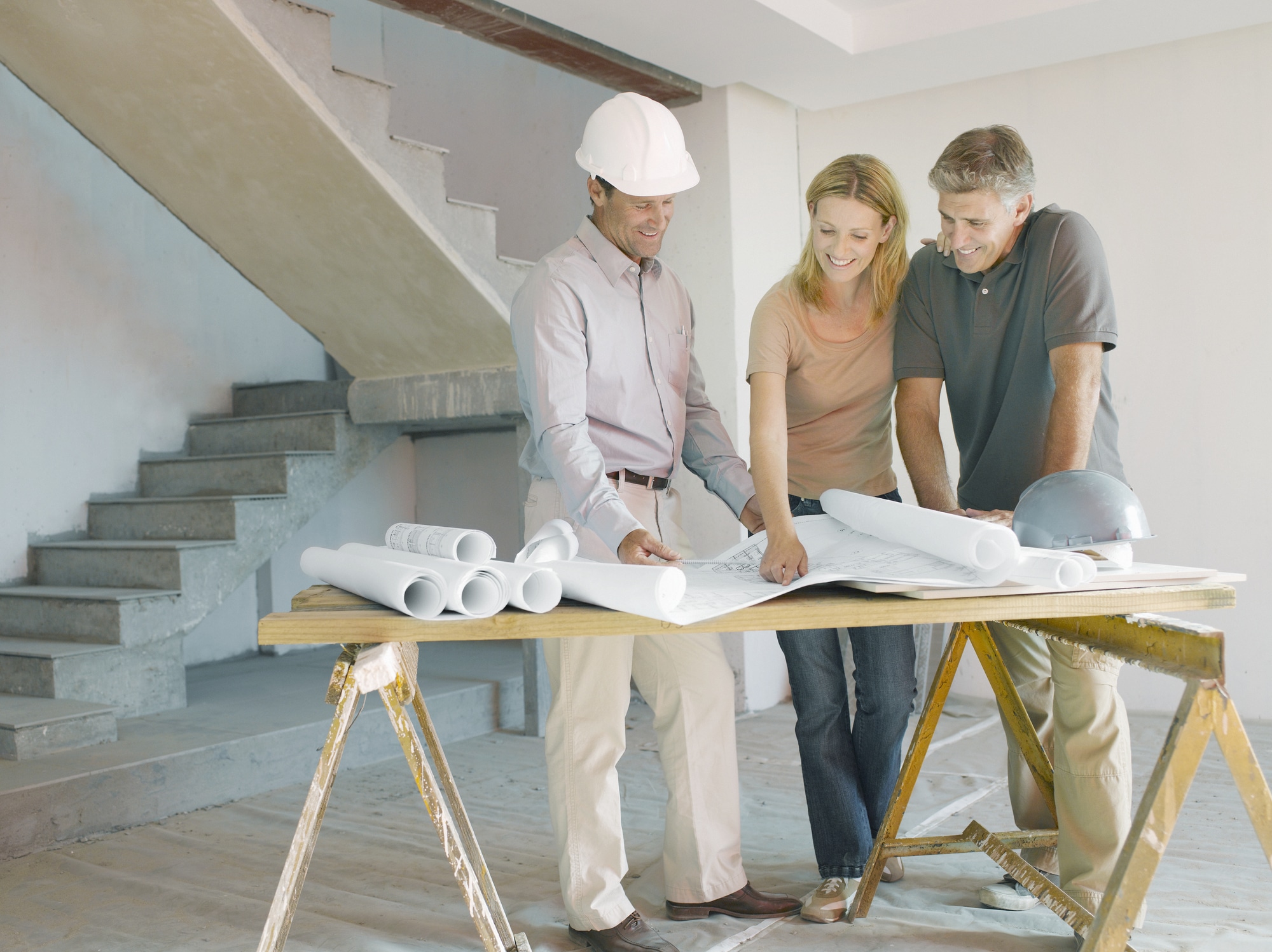 Construction foreman explaining blueprints to couple